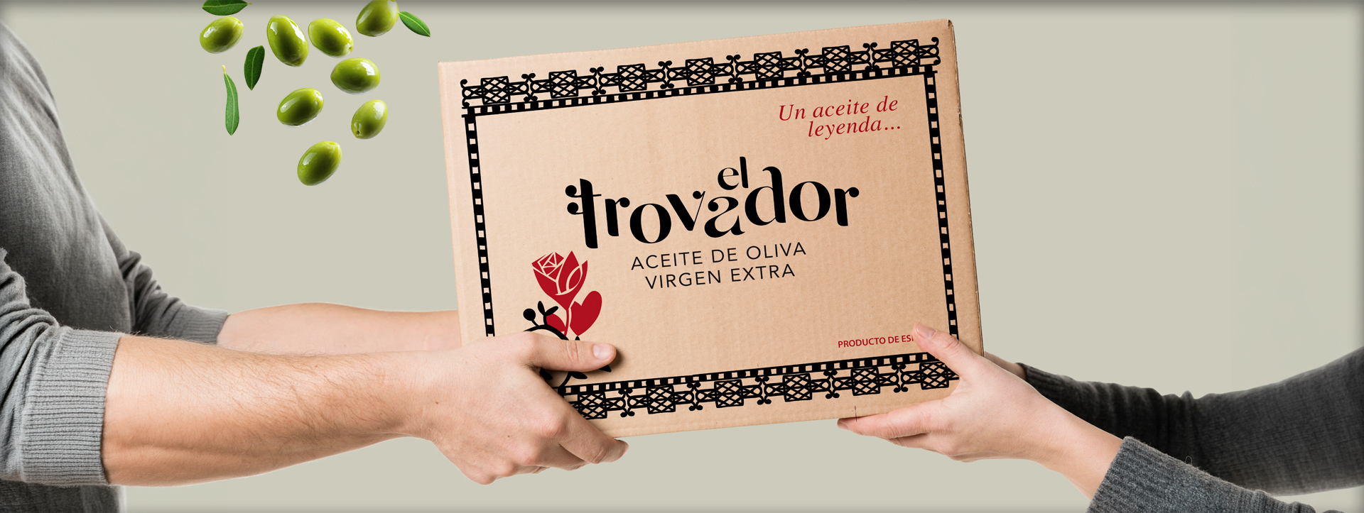 Manos entregando una caja de Aceite El Trovador con aceitunas cayendo